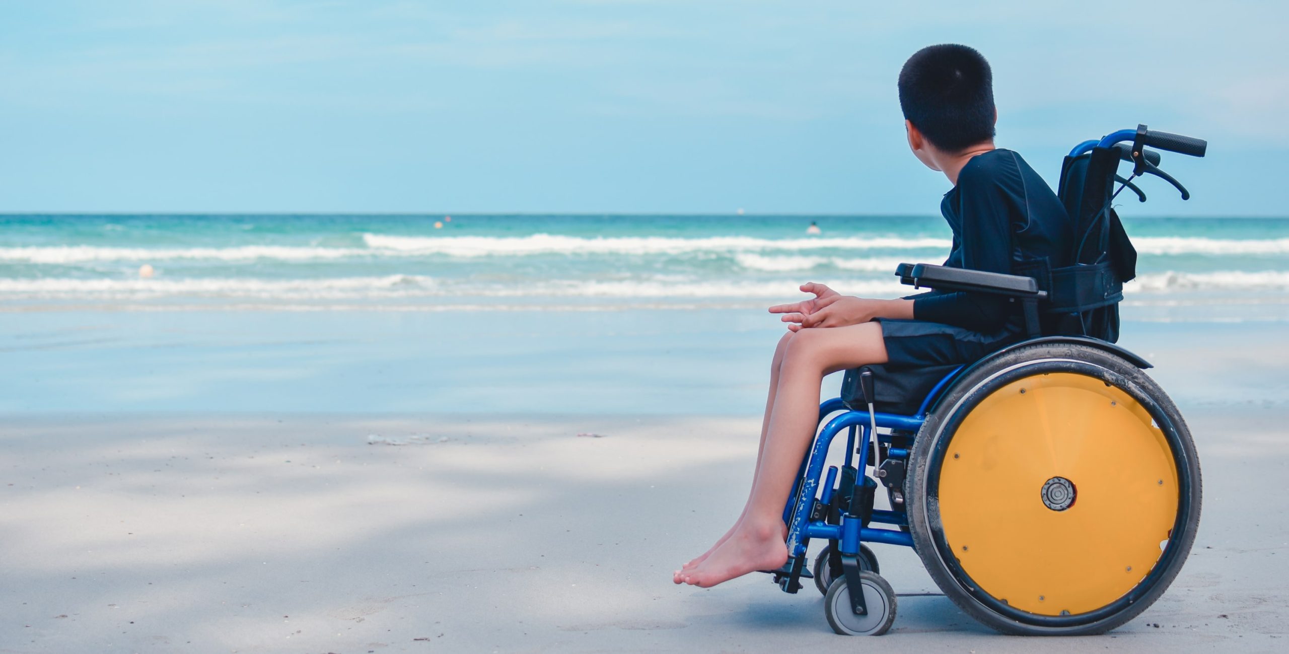 Tourist in a wheelchair by the beach