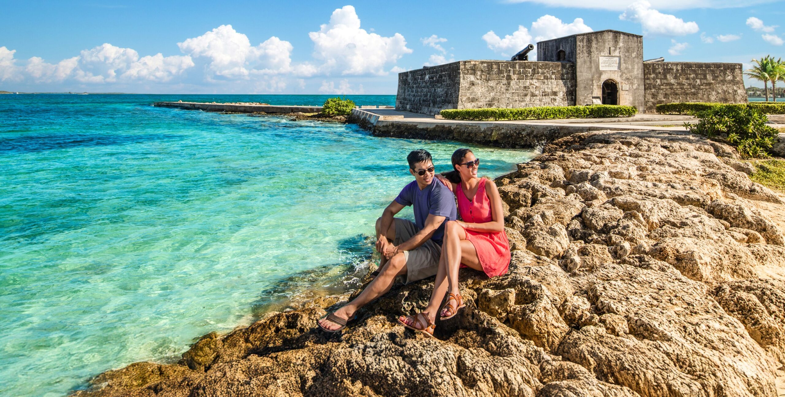 A couple at the beach in front of a historical monument.